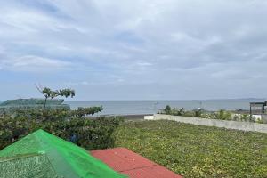 a green umbrella sitting on the grass near the beach at Lover's Point Beach Front Resort in Lian