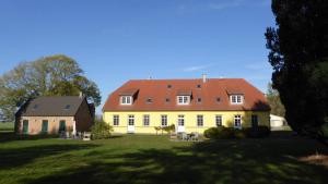 duży żółty dom z czerwonym dachem w obiekcie Gut-Rattelvitz-Galerie-E-hochwertig-Sauna-Kamin-eTankstelle-Spielscheune-15-000qm-Park-Land w mieście Gingst