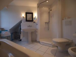 łazienka z umywalką, toaletą i wanną w obiekcie Gut-Rattelvitz-Galerie-F-hochwertig-Sauna-Kamin-eTankstelle-Spielscheune-15-000qm-Park-Land w mieście Gingst +81 zdjęć