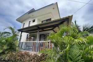 ein weißes Haus mit Palmen davor in der Unterkunft Lover's Point Beach Front Resort in Lian