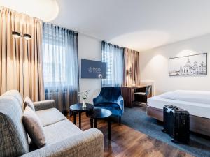 Habitación de hotel con sofá cama y escritorio en Hotel Royal en Stuttgart