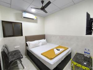 een slaapkamer met een bed, een ventilator en een stoel bij Sapna Lodging & Boarding in Mumbai