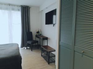 a bedroom with a bed and a desk with a television at Chambres d'hotes Grace in Guérande