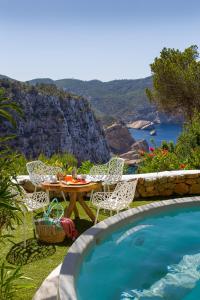 a table and chairs next to a swimming pool at Hacienda Na Xamena, Ibiza in Na Xamena