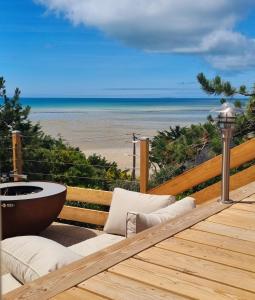 um deque com uma banheira e vista para a praia em À Saint-Pair-sur-Mer -Maison de vacances- Double Perspective - Manche em Saint-Pair-sur-Mer