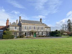 una vieja casa de piedra con un campo verde delante de ella en Wootton House, en Compton