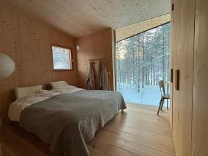 une chambre avec un lit et une grande fenêtre dans l'établissement Villa Jäkälä - An architectural wooden villa by the lake, à Rokua