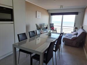 uma sala de jantar com uma mesa e cadeiras e um sofá em Apartment Noordhinder Westende em Middelkerke