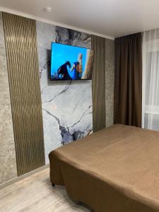 a bedroom with a bed and a tv on a wall at DEMAL HOTEL in Petropavlovsk