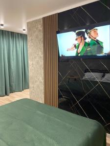 a room with a television with two people on it at DEMAL HOTEL in Petropavlovsk