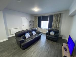 a living room with a leather couch and two chairs at Maritime House One - Hull in Hull