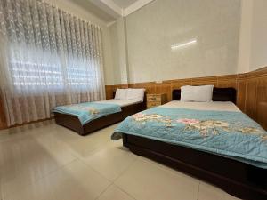 a bedroom with two beds and a window at MoTel HỒ XUÂN in Pleiku