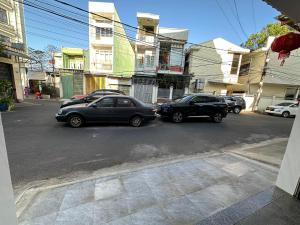deux voitures garées dans une rue en face des bâtiments dans l'établissement MoTel HỒ XUÂN, à Pleiku