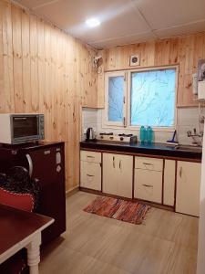 uma cozinha com paredes com painéis de madeira e um balcão em Beechwood Holiday Apartments em Mussoorie