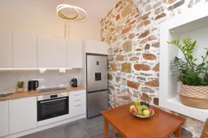 a kitchen with white cabinets and a table with a bowl of fruit at Ledio's house in Ermoupoli