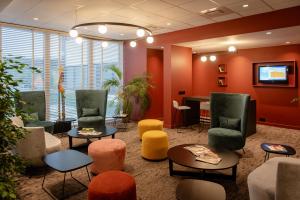 una sala de espera con sillas coloridas y una mesa en Hotel & Aparthotel Casteau Resort Mons Soignies, en Casteau