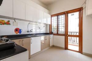 uma cozinha com armários brancos e uma grande janela em Elegant Apartment by JadeCaps Wifi Private balcony em Bangalore