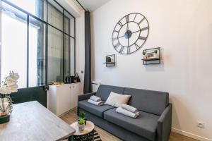uma sala de estar com um sofá e um relógio na parede em MBA - Splendide Appart - Patay 1 - Proche Bercy em Paris