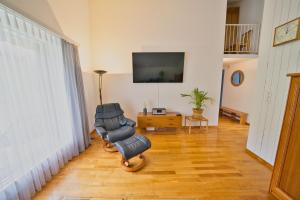 sala de estar con 2 sillas y TV de pantalla plana en Dreamview Retreat - Breathtaking Lake Views en Krattigen