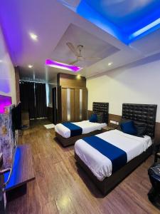 two beds in a room with purple lights on the ceilings at HOTEL COSMOS in Lucknow