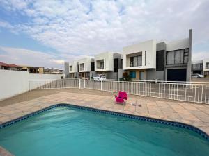a swimming pool with a chair in front of a building at Apartment close to Golf Course! in Windhoek