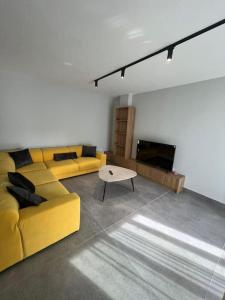 sala de estar con sofá amarillo y mesa en 5th Floor Apartment 2+1 Qerret en Golem