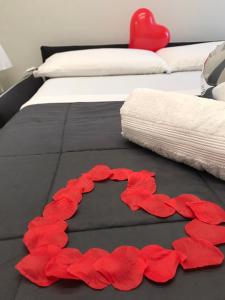 a bed with red rose petals on the floor at Maremma10 in Turin
