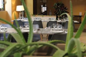 un grupo de mesas y sillas con copas de vino. en Logis Hôtel le Commerce, en Navarrenx