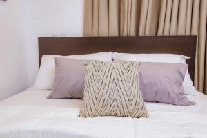 a bed with white sheets and purple pillows at Luna Loft in Tema