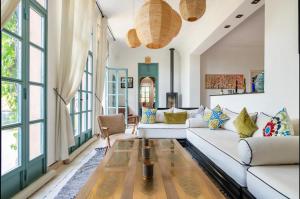 una sala de estar con muebles blancos y ventanas grandes. en Villa Magtafa en Marrakech