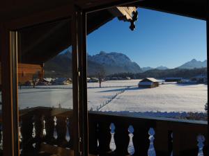 Blick auf ein schneebedecktes Feld aus dem Fenster in der Unterkunft Ferienwohnungen Alpinum in Krün