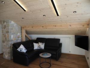 ein Wohnzimmer mit einem schwarzen Sofa und einem TV in der Unterkunft Ferienwohnungen Alpinum in Krün