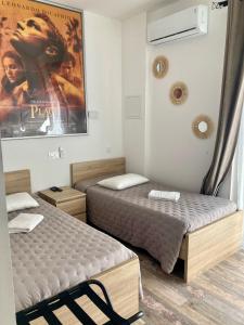 two beds in a room with a movie poster on the wall at Hôtel Le Gambetta in Vias