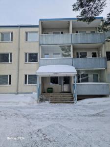 un edificio de apartamentos con un porche cubierto de nieve delante de él en Home Apartment Haukipudas, en Oulu