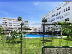 een hek met parasols en een zwembad voor een gebouw bij LIFE APARTMENTS EL PORTIL in El Portil