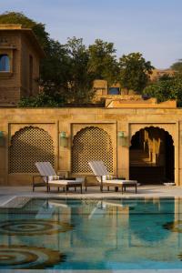 una piscina con 2 sillas junto a un edificio en Gorbandh Palace Jaisalmer-IHCL SeleQtions en Jaisalmer