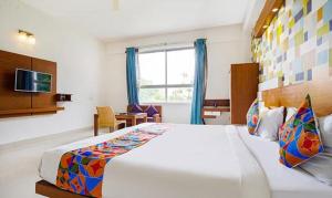 FabHotel Emirates Suites في بانغالور: غرفة نوم بسرير ابيض كبير ونافذة