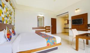 FabHotel Emirates Suites في بانغالور: غرفة نوم بسرير ومكتب في غرفة