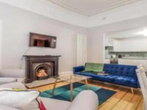 a living room with a blue couch and a fireplace at Pass The Keys Main Door 3 Bed Apartment with Free Parking in Edinburgh