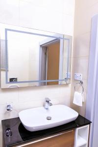a bathroom with a sink and a mirror at Rosewood Chamber in Tema
