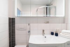 a white bathroom with a sink and a mirror at Ferienwohnung Seeschwalbe in Schilksee +7 photos