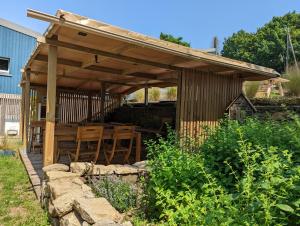 a wooden pergola with tables and chairs under it at Camping Naéco Audierne in Plouhinec