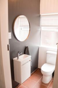 a bathroom with a white toilet and a mirror at Grace in Pretoria