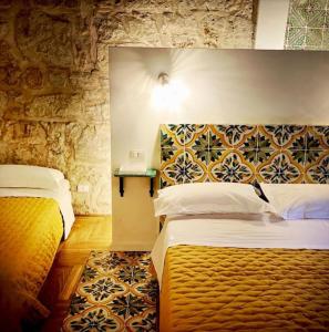 a bedroom with two beds and a stone wall at Casa Verderame in Palermo