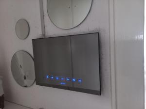 a flat screen tv on a wall with two mirrors at Ferienwohnung OLA in Homburg