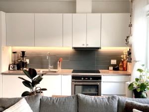 a kitchen with white cabinets and a couch at Your Perfect Aarhus Staycation in Aarhus