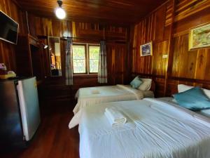 a bedroom with two beds in a wooden room at Pai Tewdoi Garden ปาย ทิวดอย การ์เด้น in Pai