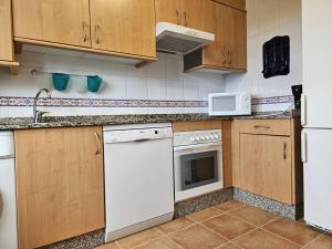 - une cuisine avec des appareils blancs et des armoires en bois dans l'établissement Casa con jardín y piscina en Muros, à Muros de Nalón