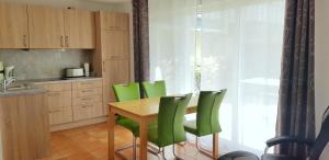 ツィングストにあるOstseeglück App9のキッチン(木製テーブル、緑の椅子付)