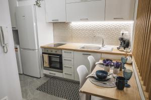 cocina con mesa de madera y nevera blanca en Alfa- Central Luxury Condo, en Katerini